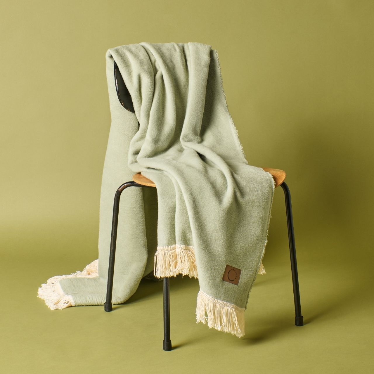 Kuscheldecke aus Baumwolle mit Fransen in Lindgrün (Stuhlansicht)